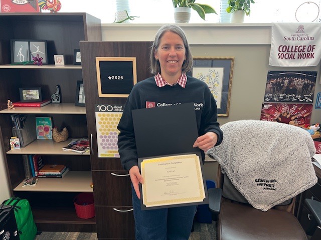 CTE Certificate Completer Avril Lail Woman standing in office holding a certificate.