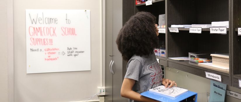 Girl grabbing a pen from the Gamecock School Supplies Pantry