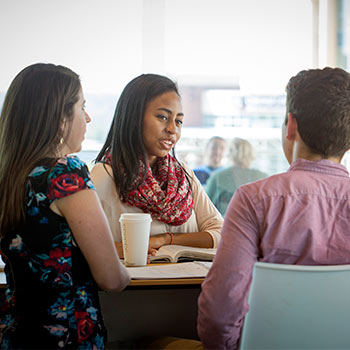 Students gathered together in a common lounge area talking over coffee.