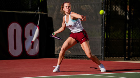 A women's tennis player hits a forehand from the baseline 