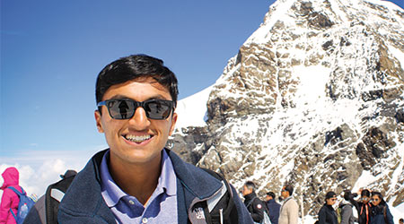 Student studying abroad in front of a snowy mountain.