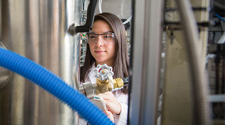 Student taking notes in front of a gage on a piece of equipment.