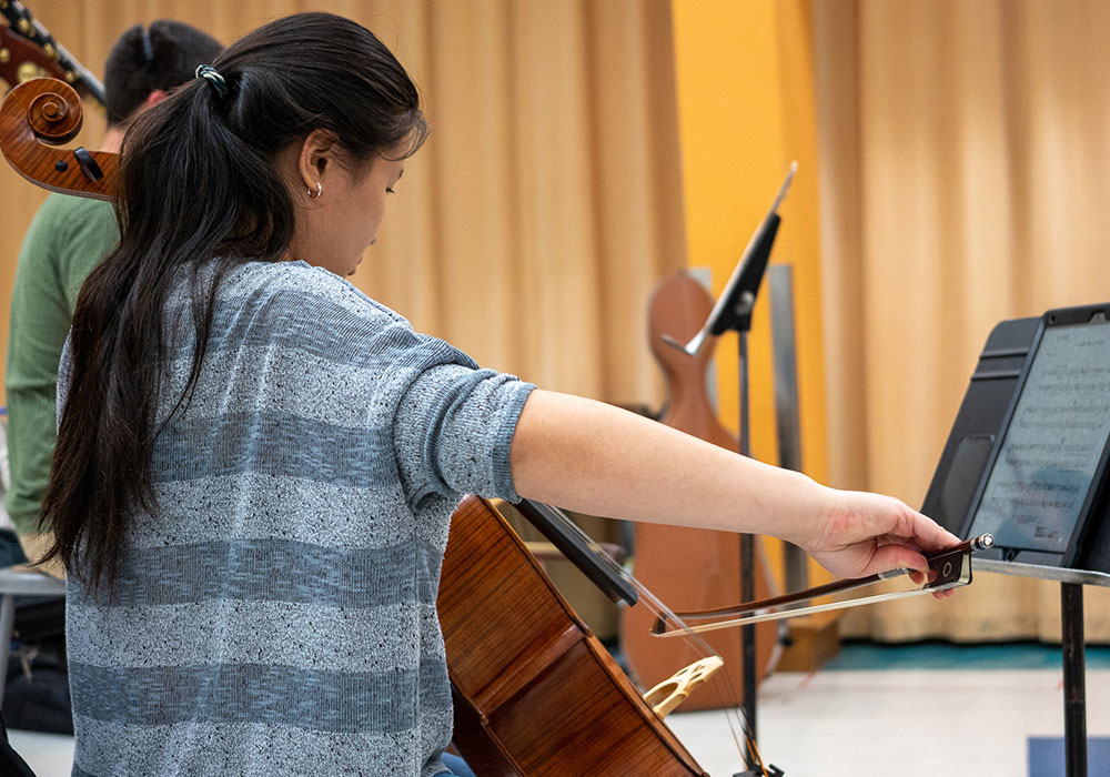 a student playing cello in a classroom