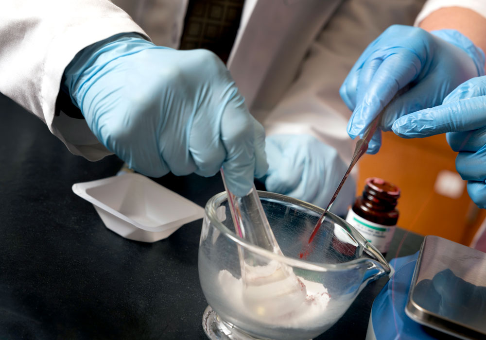 Hands mixing medicine with a mortar and pestle.