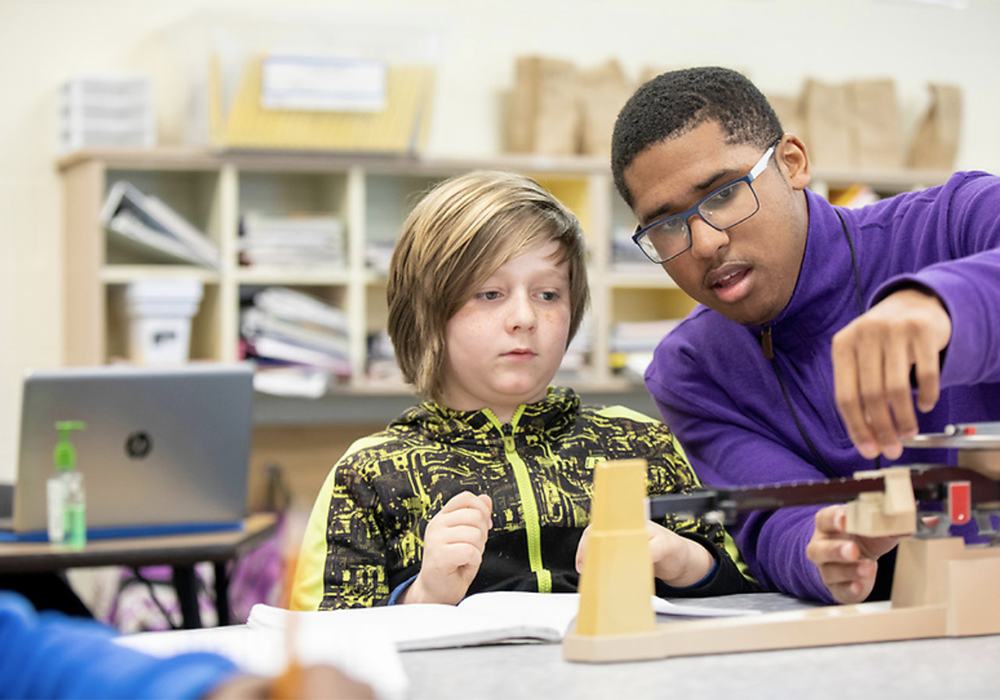 a student teacher instructs an elementary school student