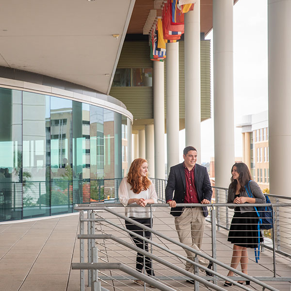 Three students standing on a balcony at the Moore School.