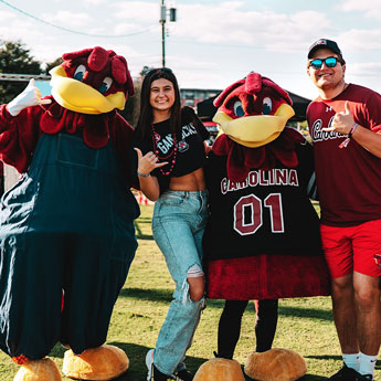 A student and her father pose for a photo with Cocky and Cocky's dad