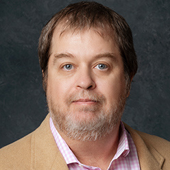 man with tan jacket on and brown hair