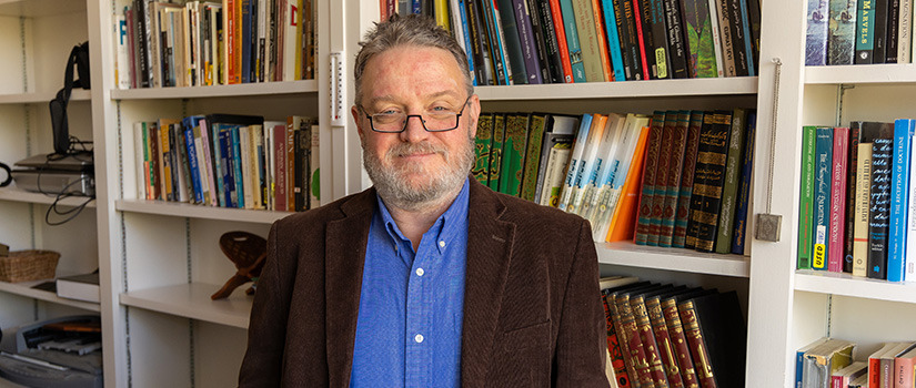 Man smiling with brown jacket and blue shirt on