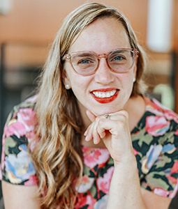 woman with blond hair and pink glasses on smiling