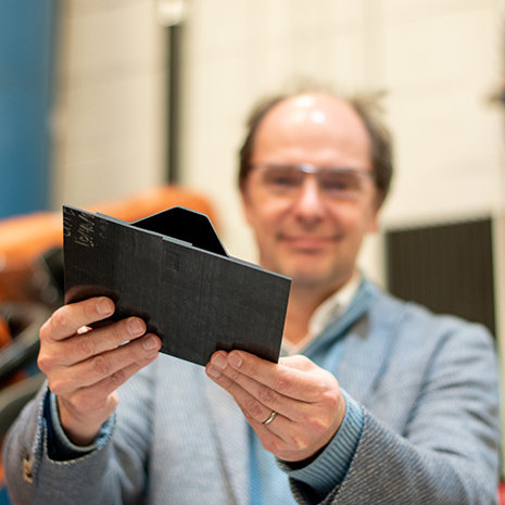 Dr. Van Tooren holds an aerospace composite up to the camera