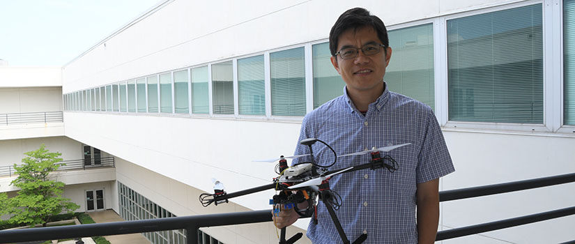 Xiaofeng Wang holding a drone overlooking the Swearingen courtyard