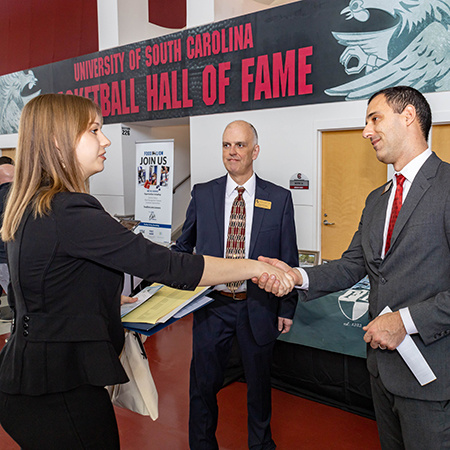 A student shakes hands with a company representative at the Experience Expo event.