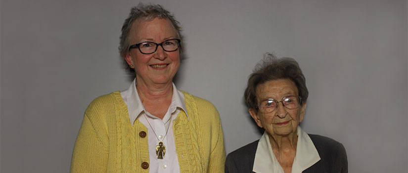 Lisa Wilcox and Sarah Leverett stand in front of a grey background