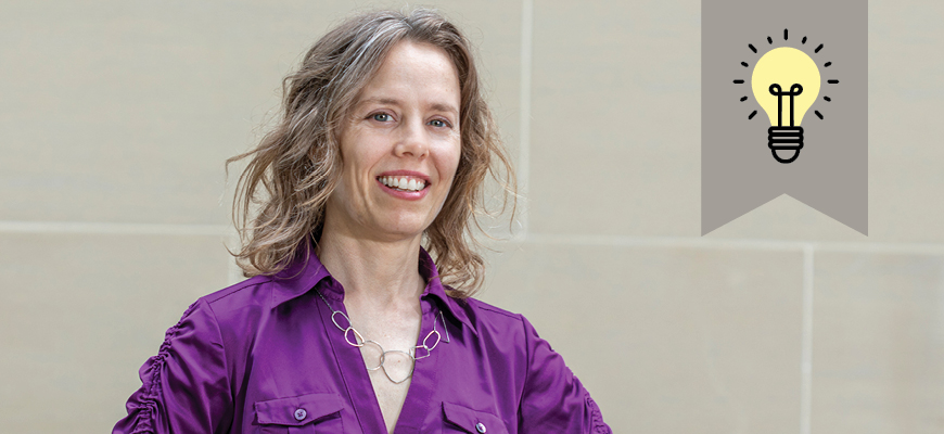 Assistant professor of studio art Naomi Falk stands in front of a wall to have her photo taken