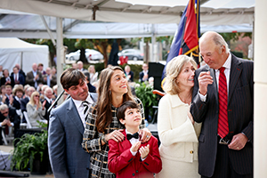 four adults and a child look at a building with a crowd in the background