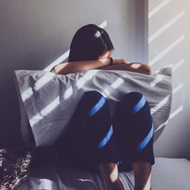 photo illustration of a young woman sitting with her head on a pillow on her lap