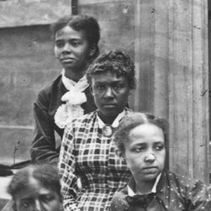 Archival image of three women sitting on the steps of a building 