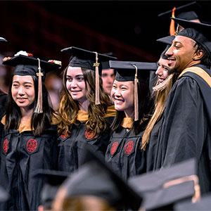 Group of students in graduation cap and gowns posing for a photo.