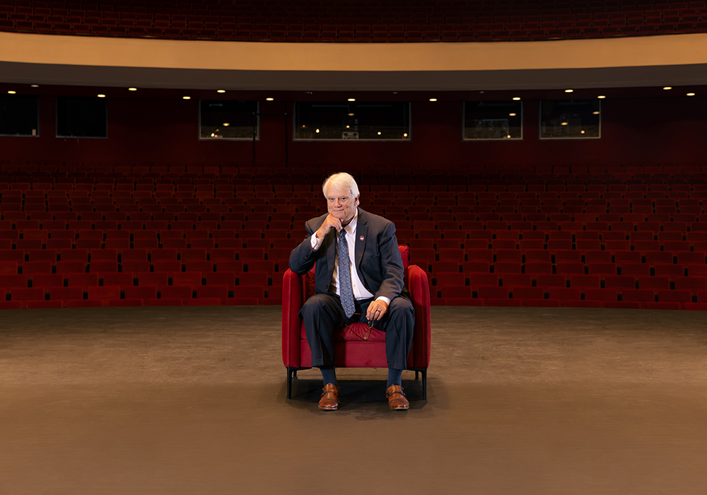 Tayloe Harding sits in a red chair on stage in the Koger Center auditorium.